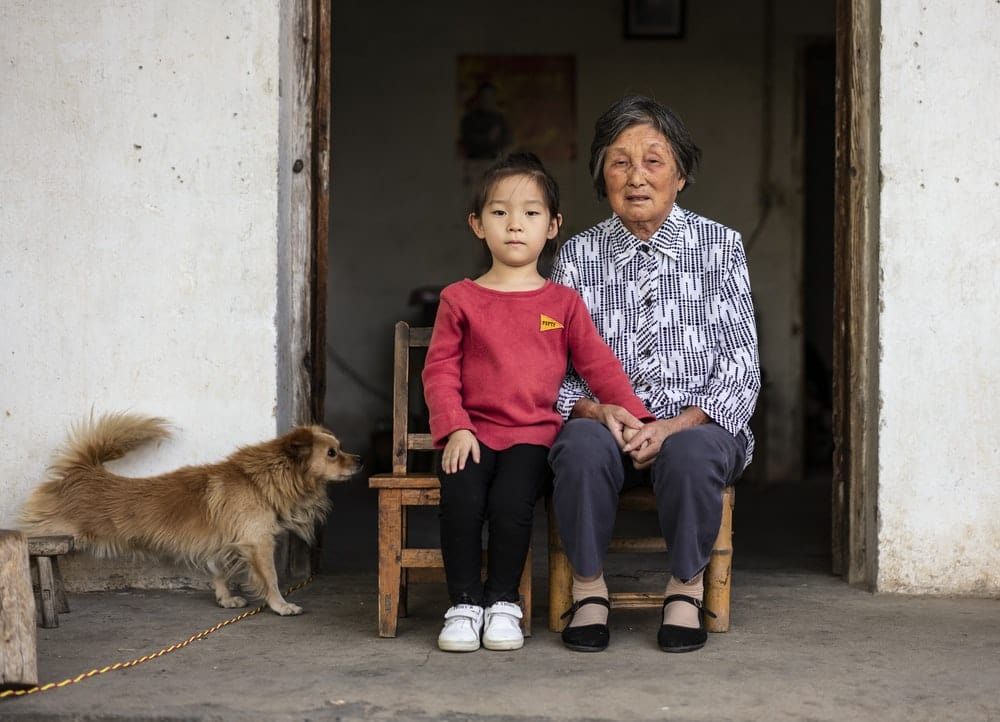 Cross Stitch | Anqing - Girl And Woman Sitting Near Brown Dog - Cross Stitched