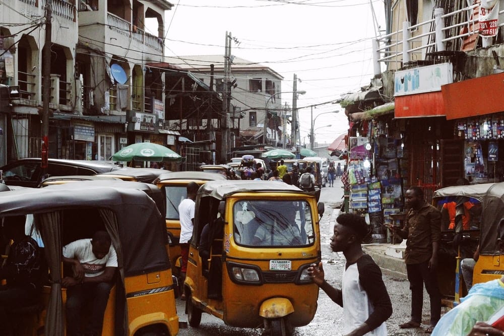 Cross Stitch | Lagos - People On Street And Different Vehicles Near Buildings During Daytime - Cross Stitched