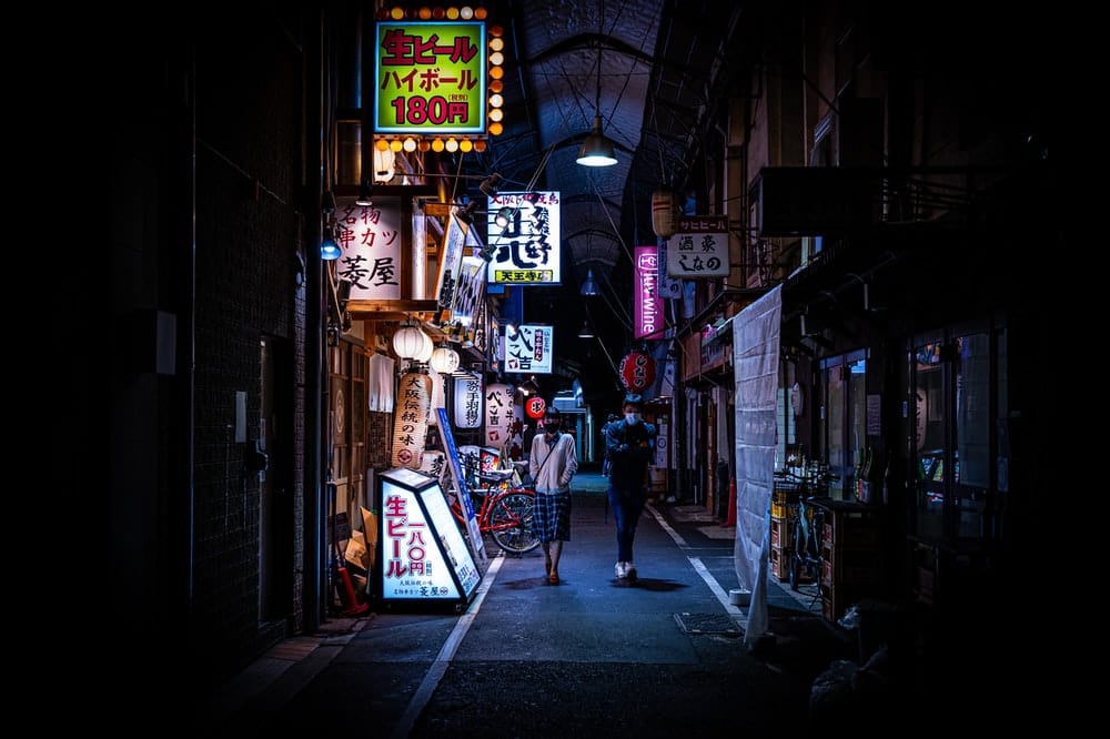 Cross Stitch | Ōsaka - Man In Black Jacket Walking On Sidewalk During Nighttime - Cross Stitched
