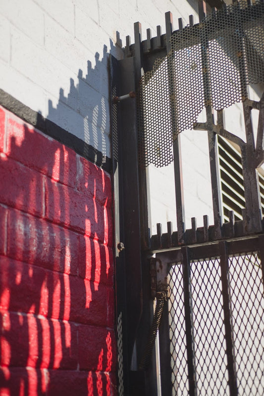 Cross Stitch | Santa Cruz - Black Metal Fence Near Red And White Concrete Building During Daytime - Cross Stitched