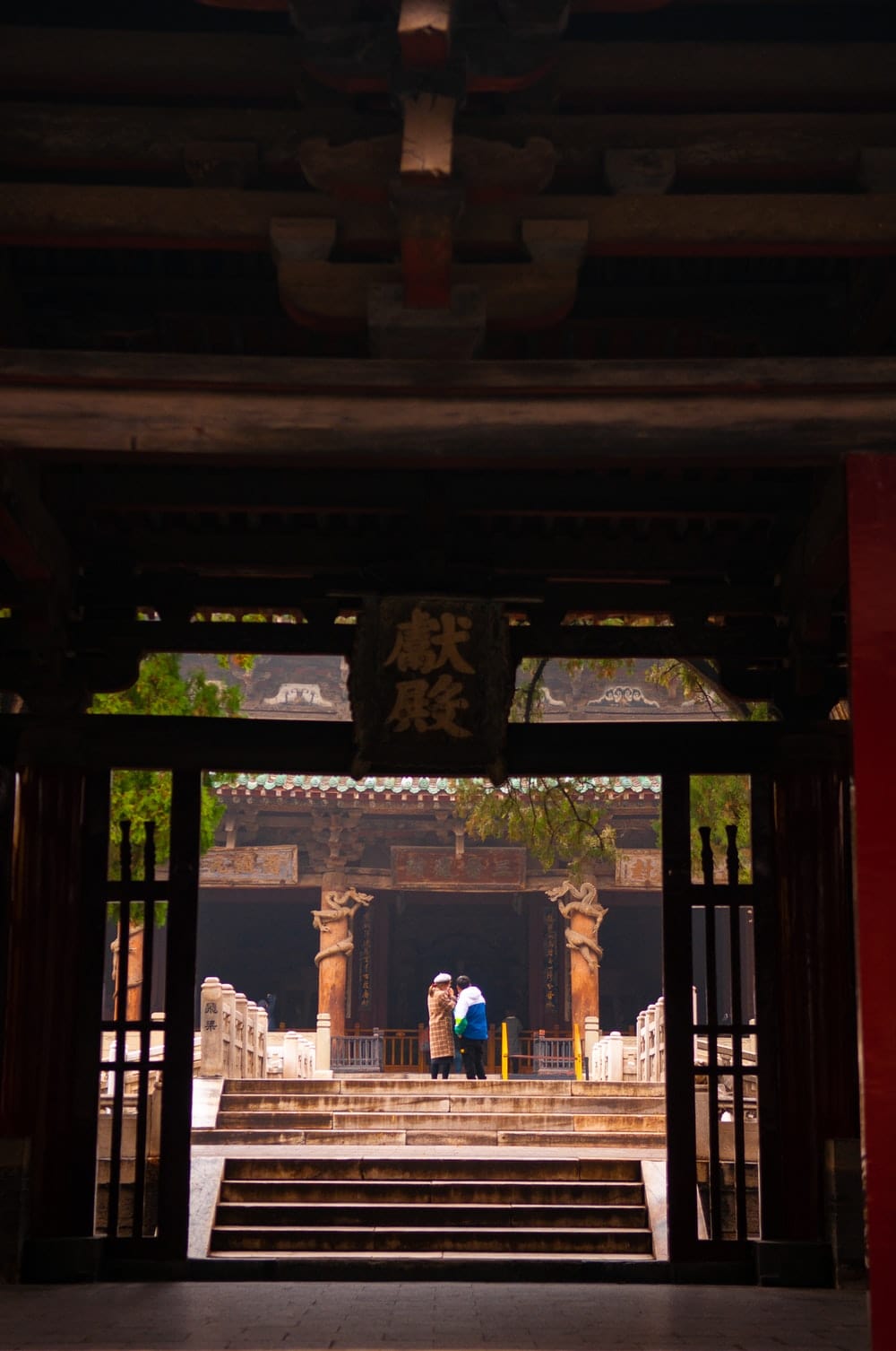 Cross Stitch | Taiyuan - Woman In Blue Dress Standing On Brown Wooden Door - Cross Stitched